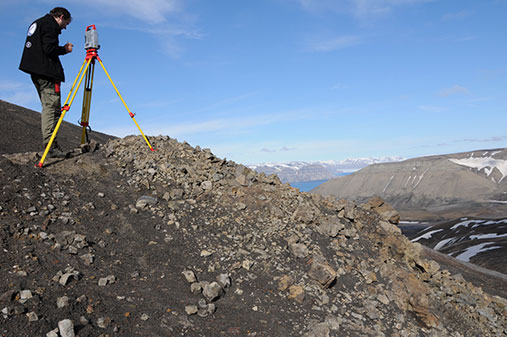 Mann med måleinstrument over landskap på Svalbard