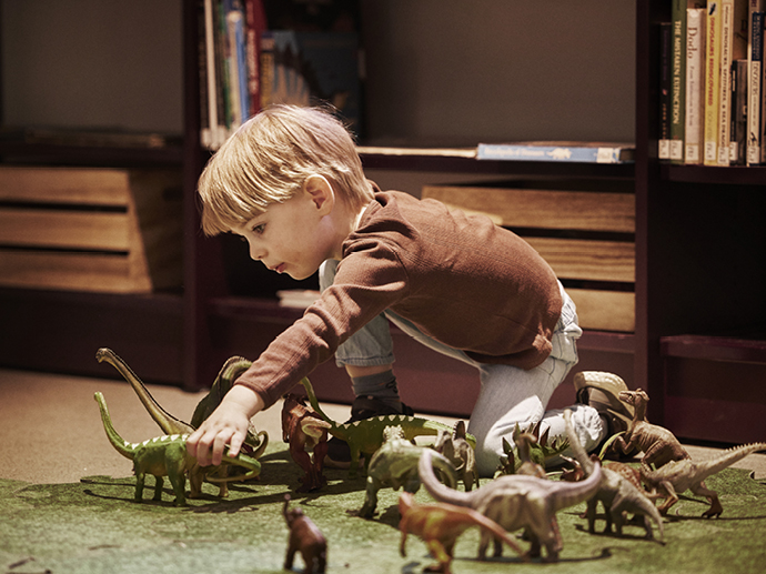 Barn leker med dinosaurfigurer i bibliotek